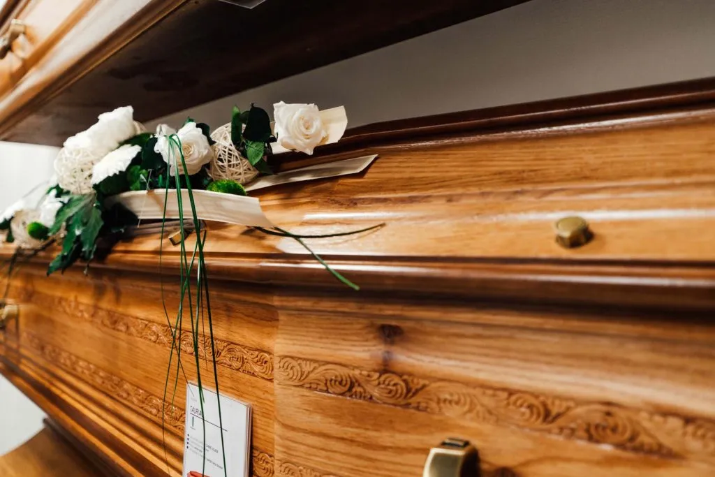 Gros plan sur un cerceuil en bois finement sculpté orné d'une composition de roses blanches